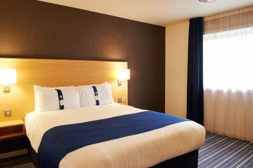 a hotel room with a large bed and a window at Holiday Inn Express Manchester Airport, an IHG Hotel in Hale