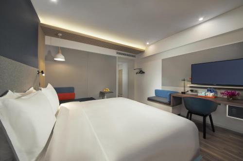 a hotel room with a large white bed and a desk at Holiday Inn Express Zhangjiagang East by IHG in Zhangjiagang
