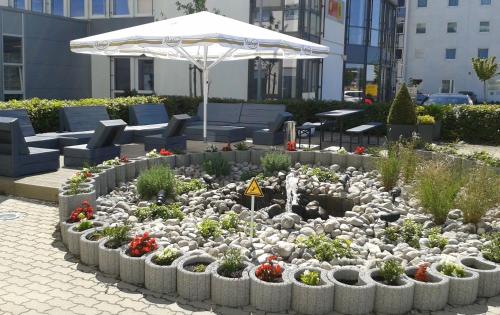 a garden with flowers and an umbrella in a city at Holiday Inn Express München Messe by IHG in Feldkirchen