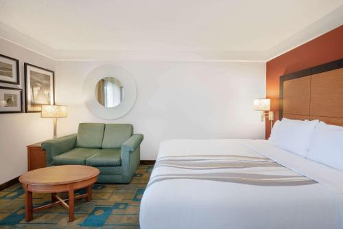 a hotel room with a bed and a chair at La Quinta by Wyndham Ocala in Ocala