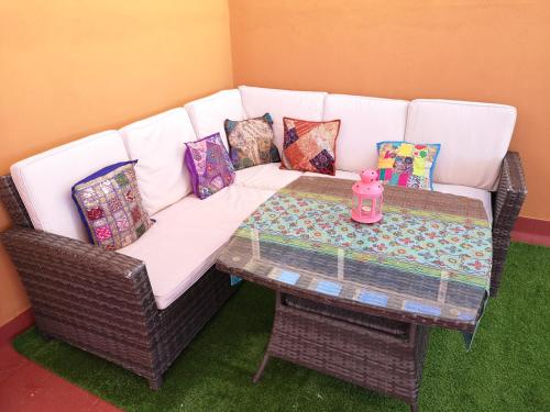 Un sofá de mimbre con una mesa y almohadas. en Spectacular views. All new with free parking, en Córdoba