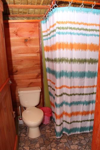 a bathroom with a toilet and a shower curtain at Yasipark - Nature Park und Ecolodge in Yásica Arriba