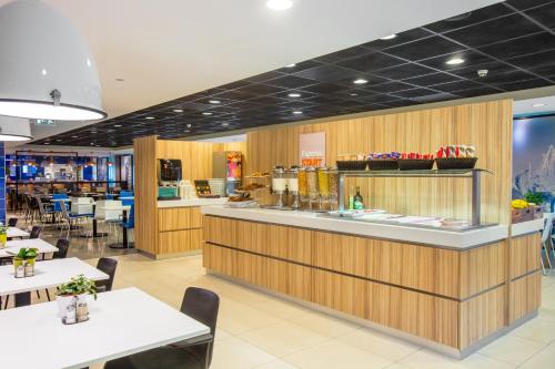 a restaurant with a counter with tables and chairs at Holiday Inn Express Rotterdam - Central Station by IHG in Rotterdam