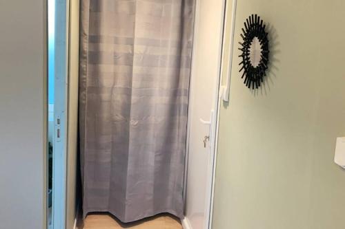 um chuveiro com uma cortina de chuveiro cinzenta num quarto em Caudry : Magnifique studio plein centre em Caudry