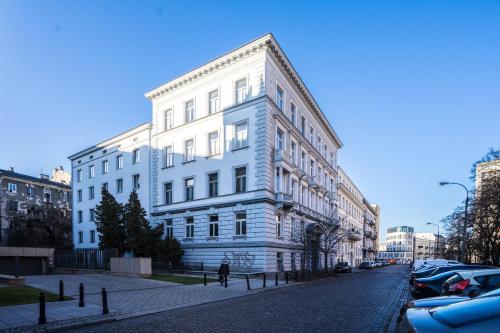 a white building on a city street with parked cars at Elegant Apartment Copernicus in Warsaw