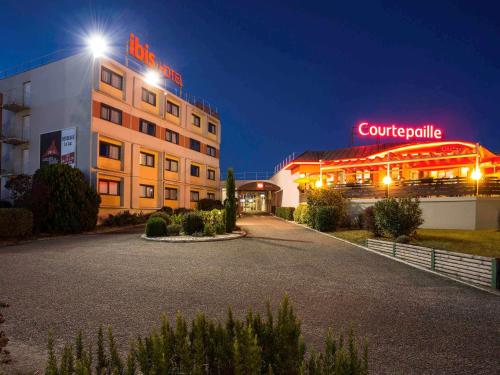 a building with a sign on top of it at night at ibis Bordeaux Lac in Bordeaux
