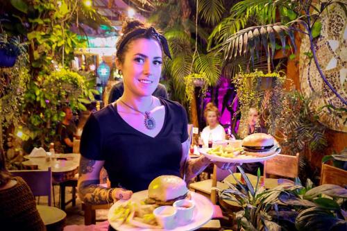 a woman holding a tray of food with two hamburgers at Los Amigos Hostel in Flores