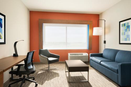 a living room with a couch and a desk and chairs at Holiday Inn Express & Suites - Beaver Dam by IHG in Beaver Dam