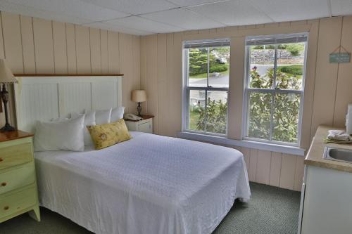 a bedroom with a white bed and two windows at NASWA Resort in Laconia