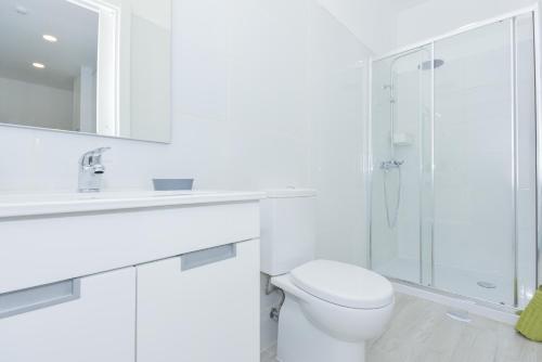 a white bathroom with a toilet and a shower at Near The Beach Apartments in Matosinhos