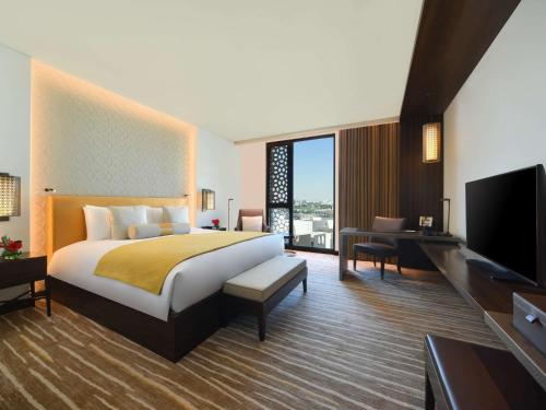 a hotel room with a bed and a flat screen tv at Alwadi Hotel Doha - MGallery Collection in Doha