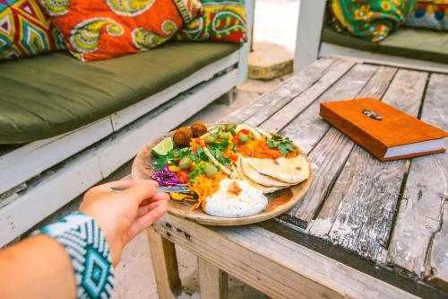 a person holding a plate of food on a wooden table at Salty's Kitesurf Village in Kilifi