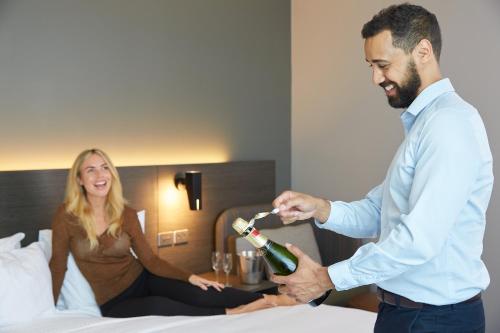 a man is giving a woman a bottle of wine at Holiday Inn Express Melbourne Southbank by IHG in Melbourne