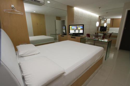 a bedroom with a large white bed and a television at Raru's Motel Cidade Jardim (Adult Only) in Natal