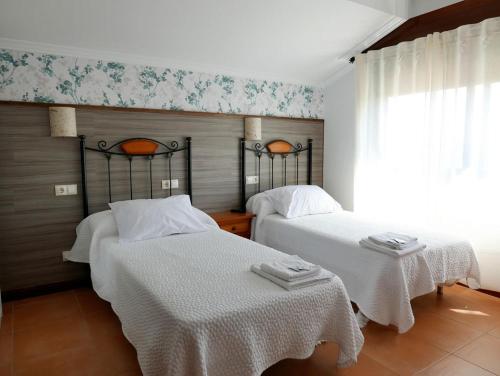 a bedroom with two beds with white sheets and a window at Pensión O Escondidino in Baiona