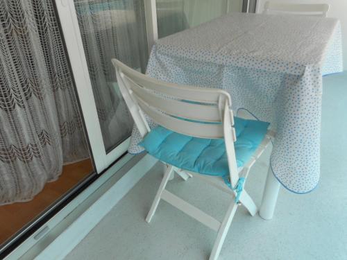 una silla blanca sentada junto a una mesa con un cojín azul en T2 Bassin d'Arcachon, 100m plage, centre-ville en Andernos-les-Bains