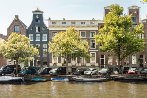 a group of boats parked next to a river with buildings at Empire suites roof terras in Amsterdam
