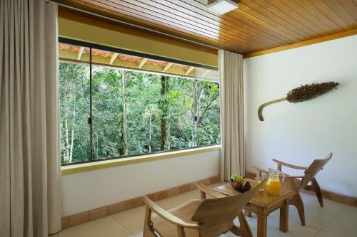 
a living room with a table, chairs and a window at Eco Resort Hotel Villa São Romão in Lumiar
