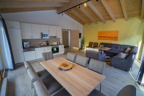 a kitchen and living room with a wooden table and chairs at Alpenhof Chalets in Gerlos
