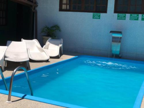 a swimming pool with white chairs and a swimming pool at Pousada Rancho Verde in Porto Seguro