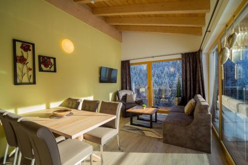 a dining room with a table and chairs and a couch at Alpenhof Chalets in Gerlos