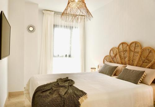 ein weißes Schlafzimmer mit einem großen Bett mit einem Kopfteil aus Holz in der Unterkunft MADMAR Maria Zambrano in Málaga