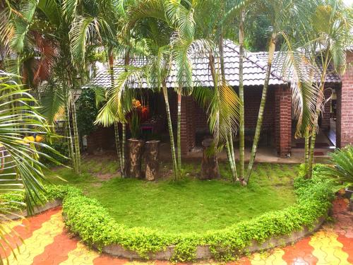 a house with palm trees and a green yard at Anandvan Holiday Homes, Wai in Wai