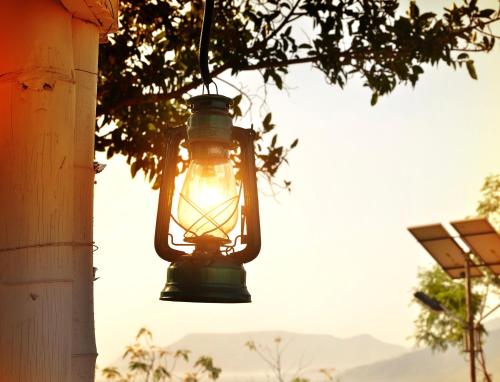a lantern hanging from a building with the sun shining at Anandvan Holiday Homes, Wai in Wai