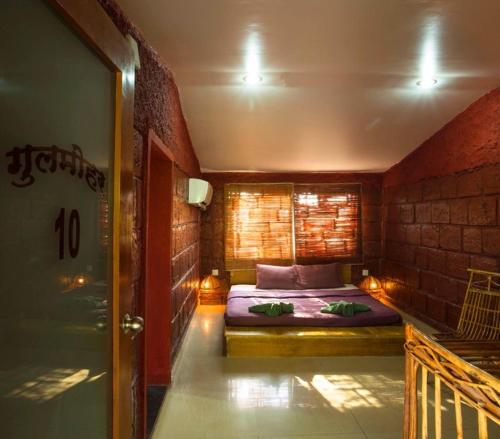 a small bedroom with a bed in a brick wall at Anandvan Holiday Homes, Wai in Wai