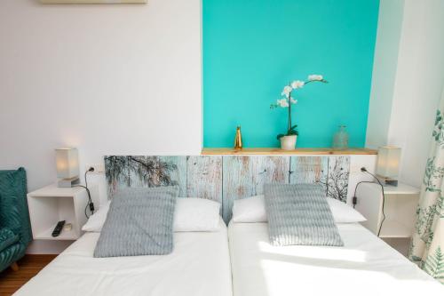 馬拉加的住宿－Your home by the sea，一间卧室设有两张床和蓝色的墙壁