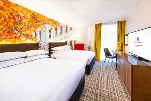 um quarto de hotel com duas camas e uma televisão de ecrã plano em Millennium Gloucester Hotel London em Londres