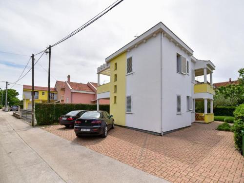Biały i żółty dom z samochodami zaparkowanymi na podjeździe w obiekcie Apartment in Suko an near Sandy Beach w Sukošanie