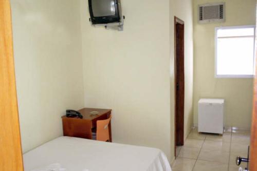 1 dormitorio con 1 cama y TV en la pared en Hotel Morada do Sol en Araxá