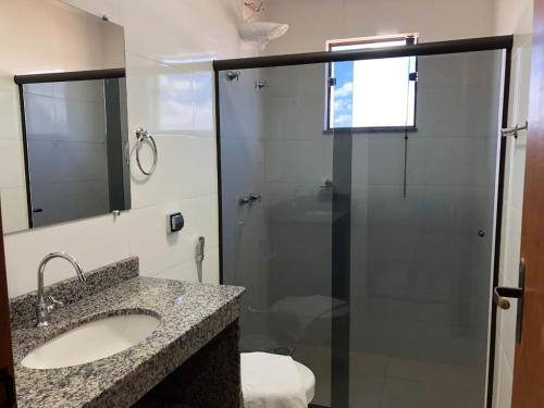 uma casa de banho com um lavatório e um chuveiro com um espelho. em Hotel Martins em Pouso Alegre