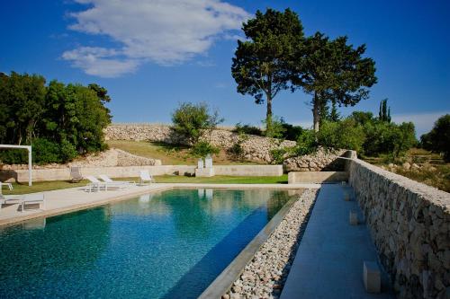 a swimming pool in a yard with a stone wall at Podere Santa Chiara in Otranto