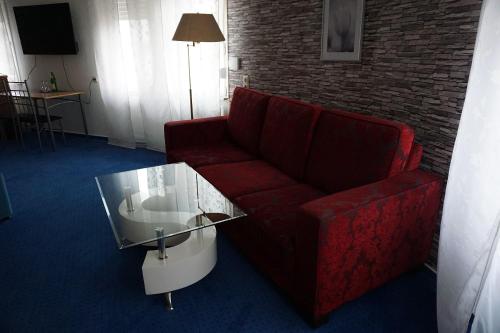 a living room with a red couch and a glass table at Hotel Haarener Hof in Bad Wünnenberg