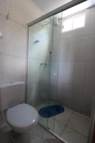 uma casa de banho com um WC e uma cabina de duche em vidro. em Pousada Portalcion em Goiás