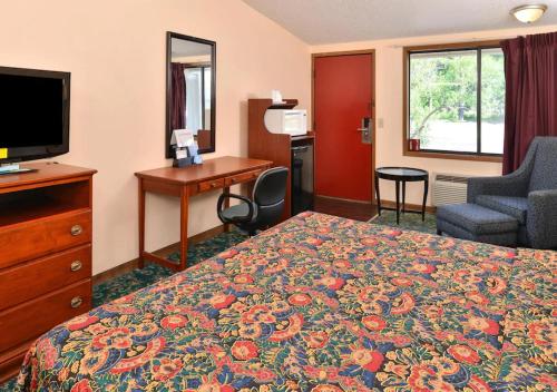 a hotel room with a bed and a desk and a television at Nation's Inn Kinston in Kinston