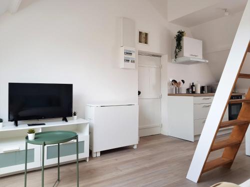 une petite cuisine blanche avec une télévision et un tabouret dans l'établissement FleuryBis - Appartement calme proche de Rouen, à Déville-lès-Rouen