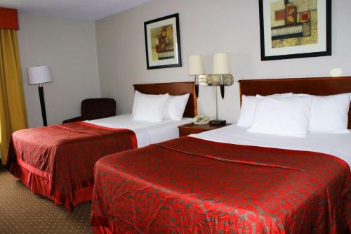 a hotel room with two beds with red sheets at Days Inn & Suites by Wyndham Bloomington/Normal IL in Bloomington