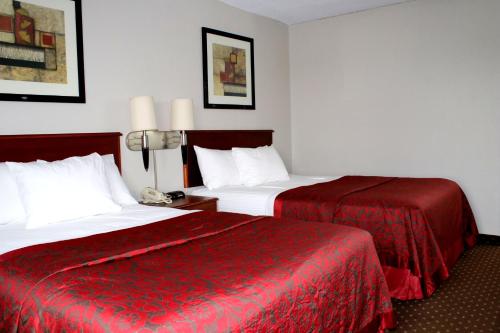 a hotel room with two beds with red sheets at Days Inn & Suites by Wyndham Bloomington/Normal IL in Bloomington