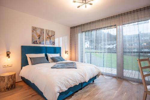 ブリクセン・イム・ターレにあるKaiser Appartement Brixen im Thaleの大きなベッドと大きな窓のある寝室