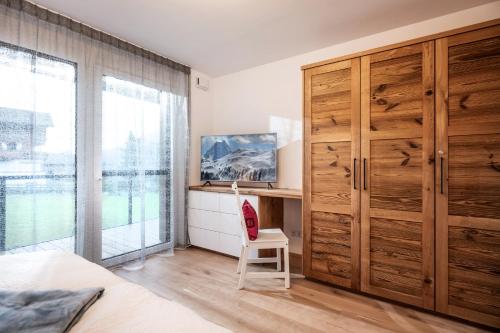 a bedroom with a large wooden closet and a chair at Kaiser Appartement Brixen im Thale in Brixen im Thale