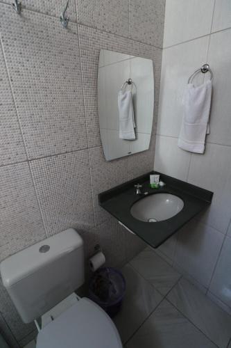 a bathroom with a sink and a toilet and a mirror at Pousada Portalcion in Goiás