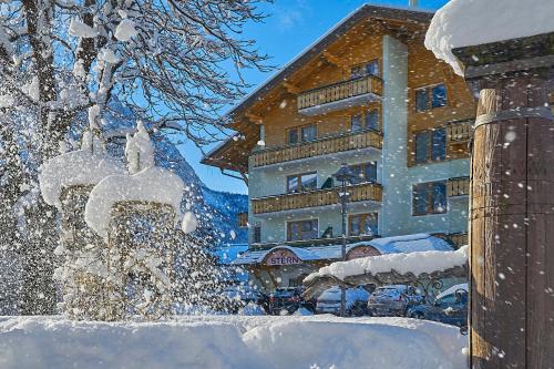 a building covered in snow in front of a building at Hotel Stern in Ehrwald