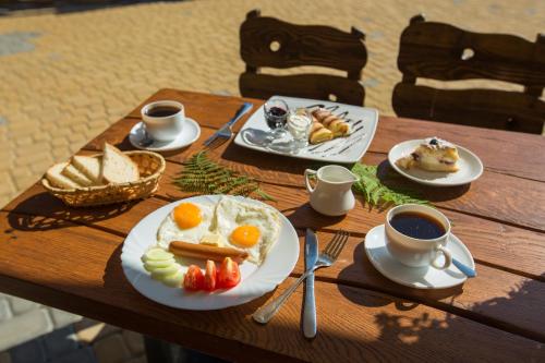 une table avec des assiettes de nourriture et des tasses de café dans l'établissement Вілла Тростян Резорт, à Slavsko