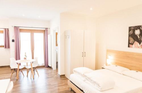 a white bedroom with a bed and a table at Agriturismo Riva dei Coz in Segusino