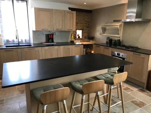 a kitchen with a black counter and chairs in it at Domaine du Colombier, Gite La Liberte in Larroque