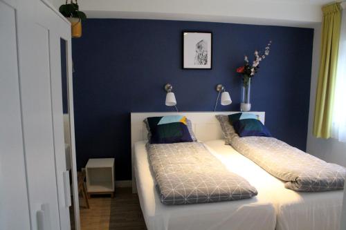 1 dormitorio con 2 camas y pared azul en Landzicht, en Woubrugge