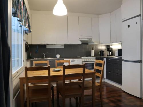 a kitchen with white cabinets and a wooden table and chairs at Kotipaljakka in Kotila